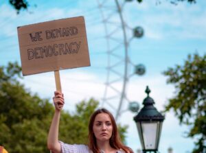 woman holding placard 'we demand democracy'