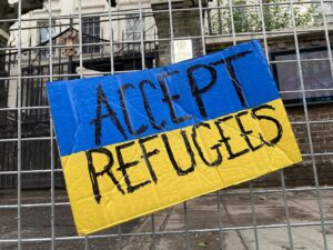 placard: accept refugees on background of Ukraine flag